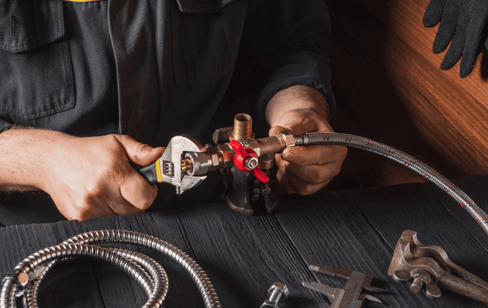 Professional gas fitter in Perth repairing a flexible gas pipe with tools.